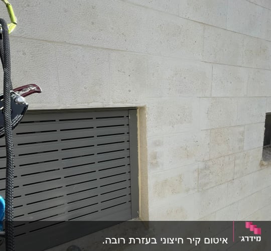 אדם בעבודות גובה ליד חלון עם תריסים